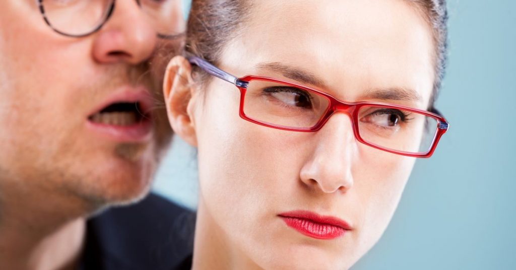 man whispering into a woman's ear