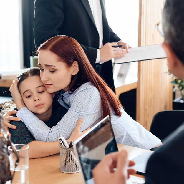 Woman hugs little girl sitting in lawyer's office for divorce.