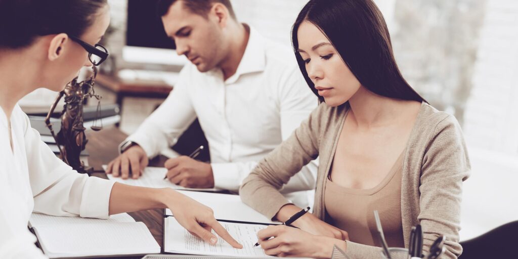 Couple signing devorce papers with divorce lawyer.