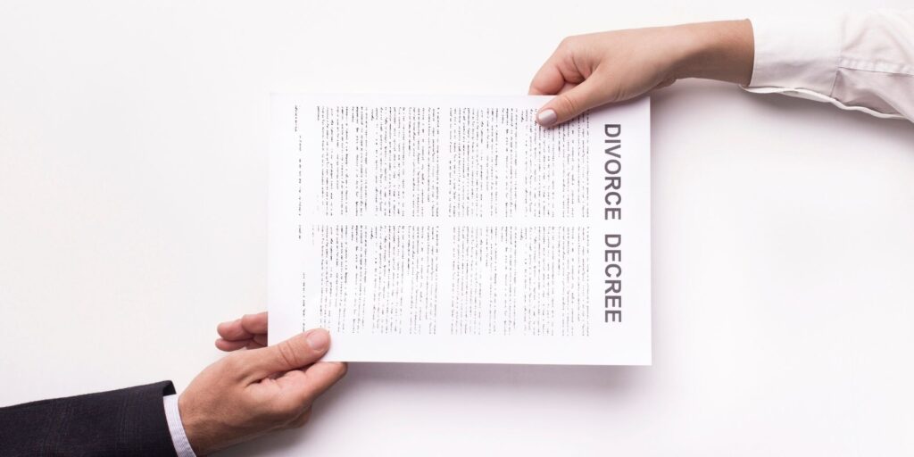two hands holding a paper saying divorce decree