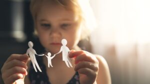Child holding paper figure cutouts of two parents holding hands with their child