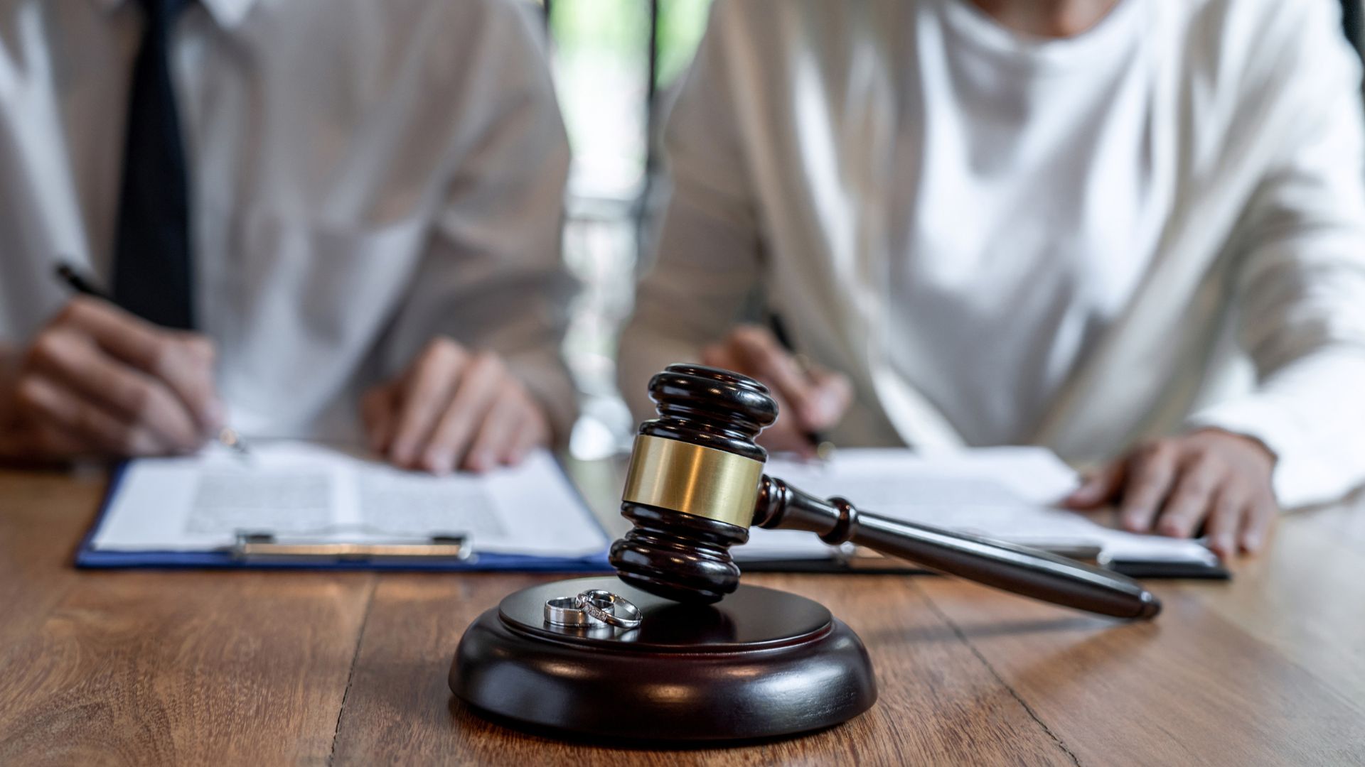 Two people sitting at a table with a gavel and paperwork on it