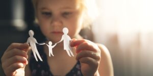 daughter holding paper cut out dolls of family