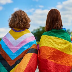 two people draped in LGBTQ plus flags