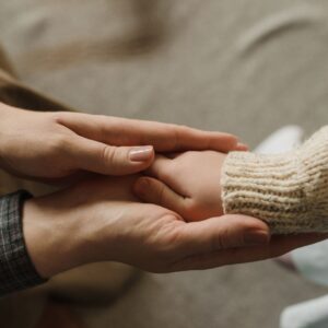 A parent holding a child's hand.