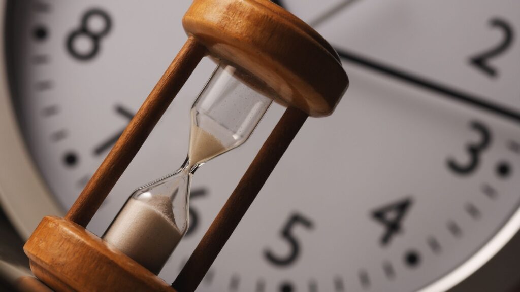 an hourglass with a clock in the background