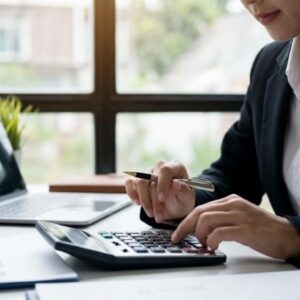 A professional focuses on a calculator screen in an office.
